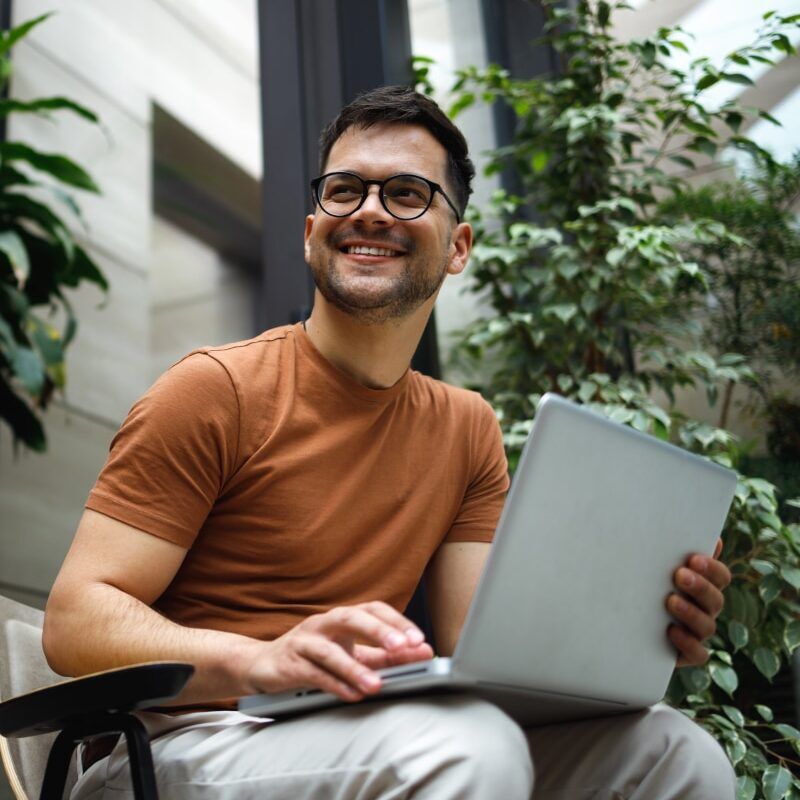 Portrait Of A Successful Young Man Sitting In The Armchair In The Modern Green Building Lobby And Working On His Laptop 1326251444 Portrait of a successful young man sitting in the armchair in the modern green building lobby and working on his laptop.